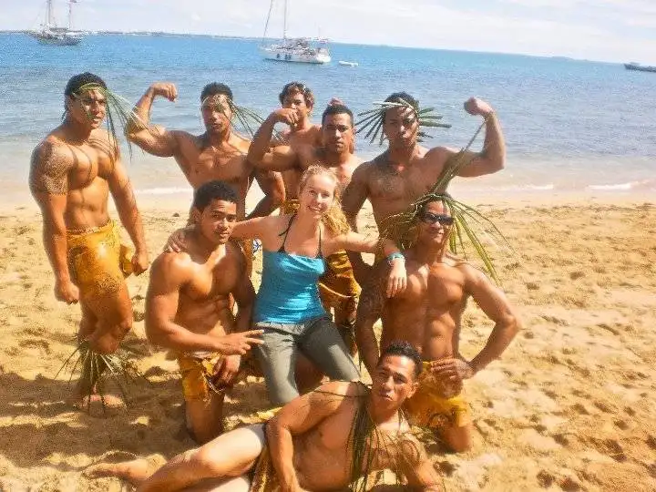 A group of people from Tonga posing for a traditional photo on the beach, showcasing their culture.