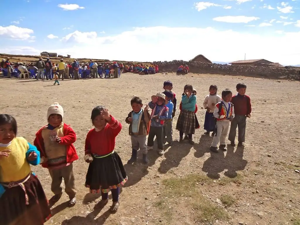 a group of children standing in a dirt field.