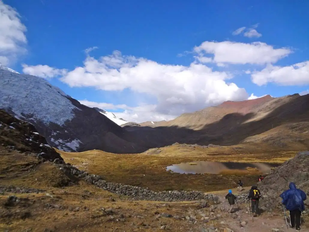 Apu Ausangate trekking trip by a group of people in the mountains near a lake.