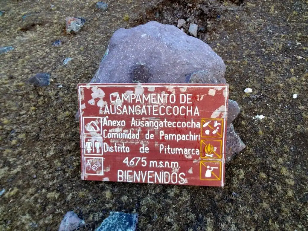 a sign sits on a rock along the Ausangate trekking route.
