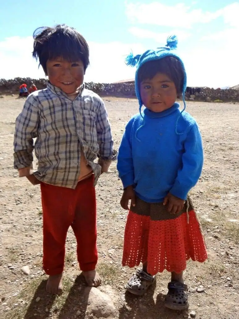 Two children standing in a dirt field during an Apu Ausangate trekking expedition.