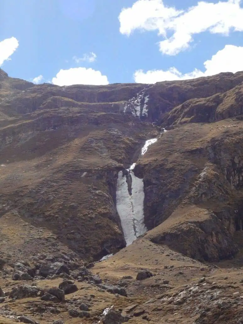 Apu Ausangate trekking unveils a majestic mountain adorned with a scenic waterfall at its core.