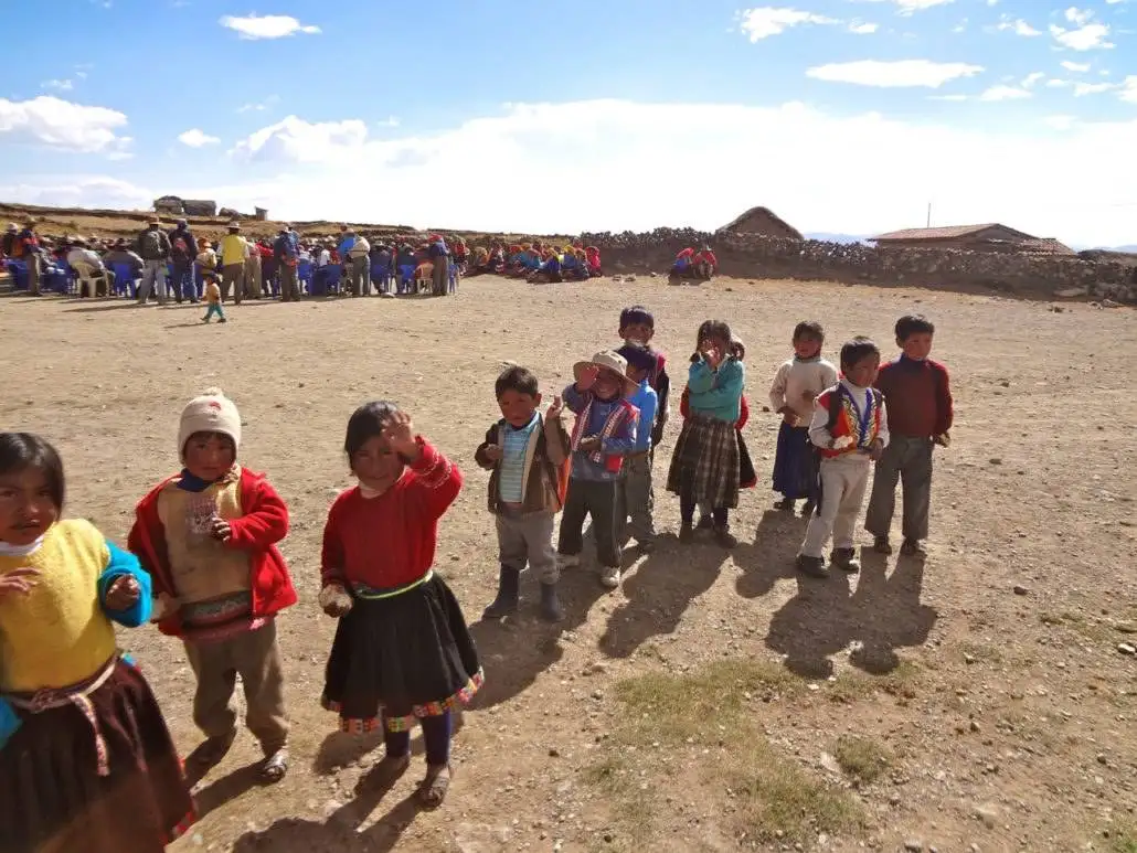 Apu Ausangate trekking expedition featuring a group of children standing in a dirt field.