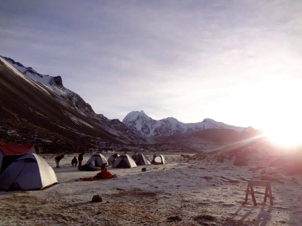 Apu Ausangate trekking group of tents in a snowy area with mountains in the background.