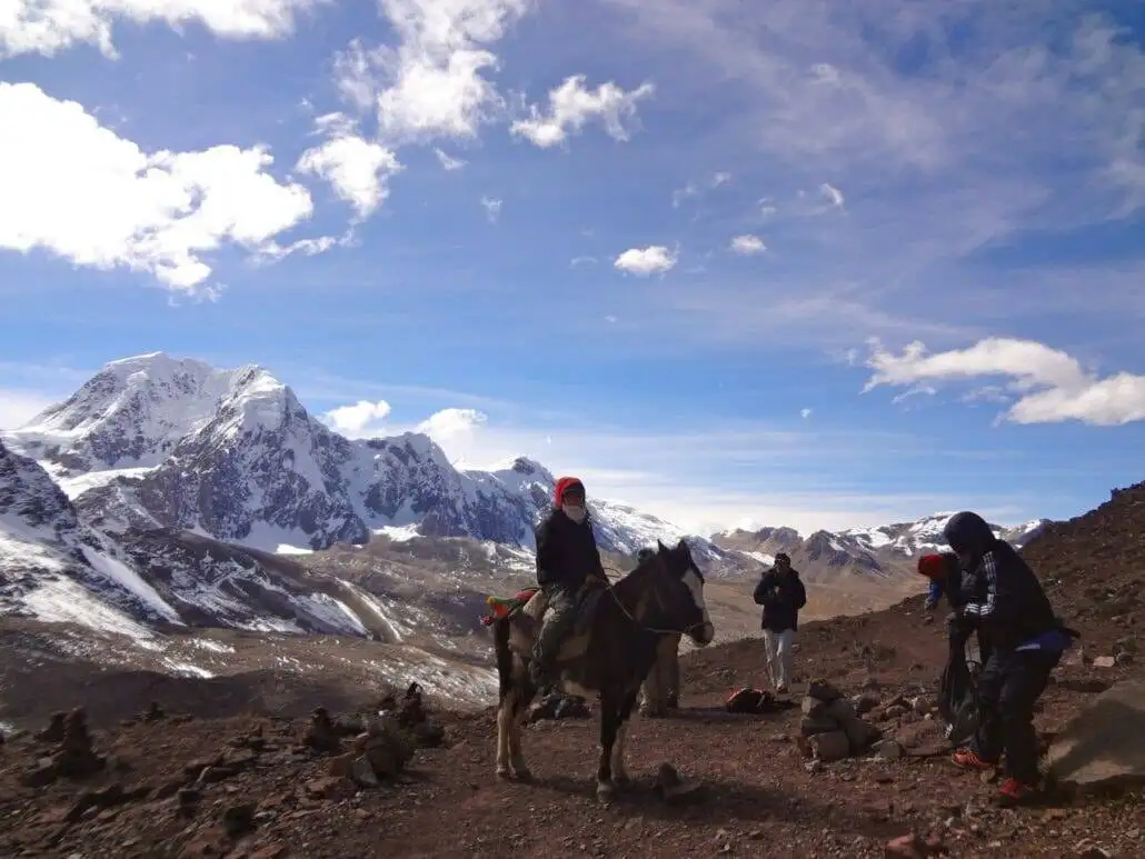 a group of people on horseback trekking through the Ausangate mountain trail.