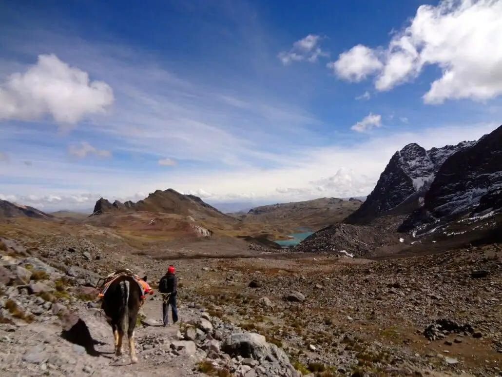a man is trekking with a horse on the Ausangate trail.