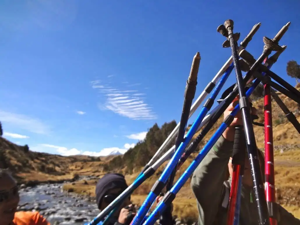 A group of people standing next to a stream during the Apu Ausangate trekking adventure.