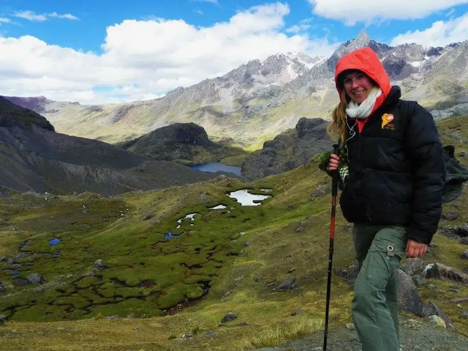 a woman in a red jacket trekking on top of the Ausangate mountain.