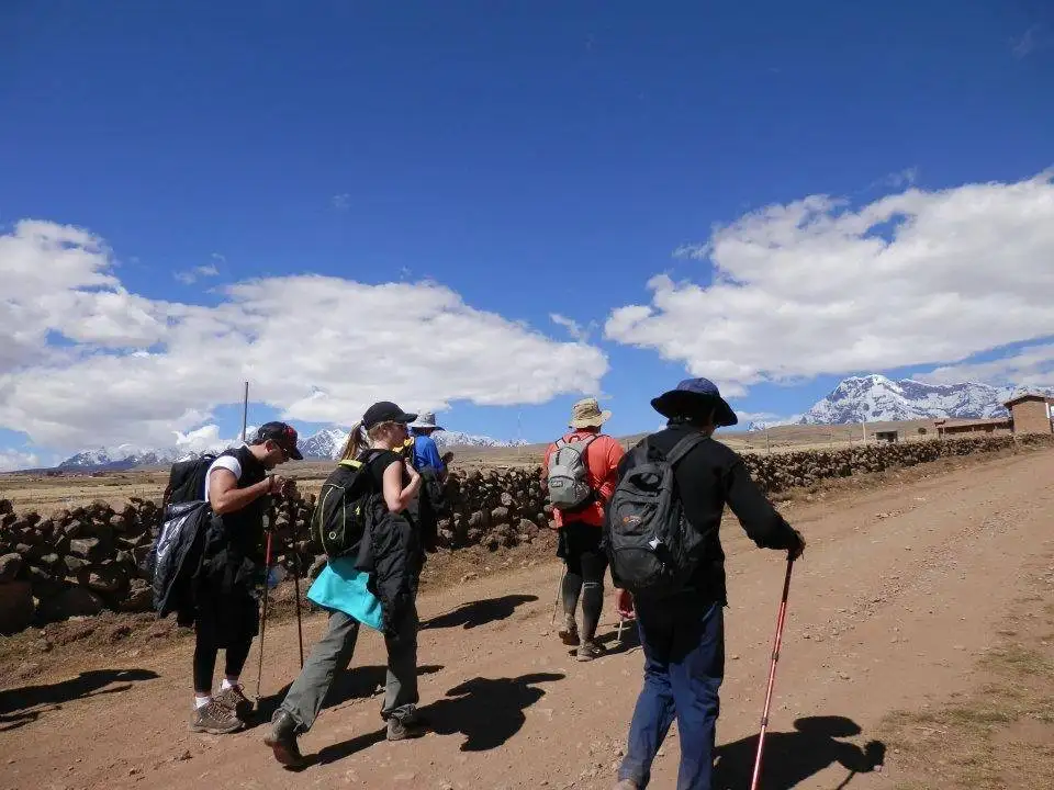 Apu Ausangate trekking group walking down a dirt road with mountains in the background.