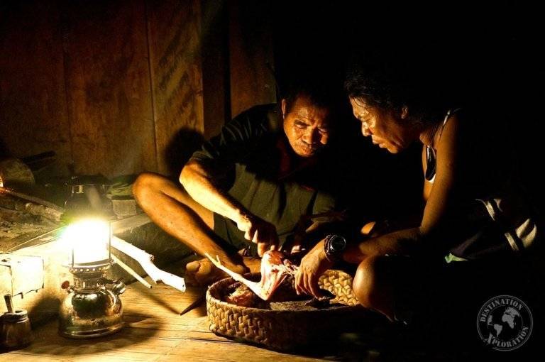 Two people sitting in a dark Belaraghi room with a lamp.