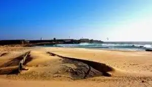 A Tarifa travel guide featuring a sandy beach with a captivating castle backdrop.