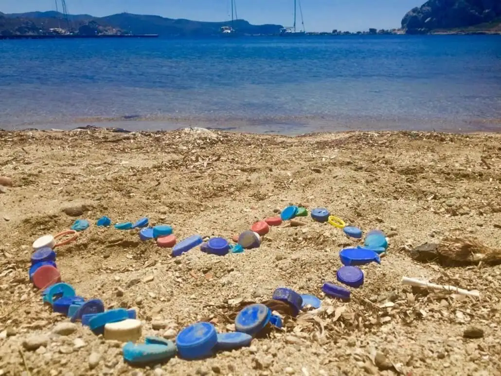 a heart made of colorful glass beads on the beach.