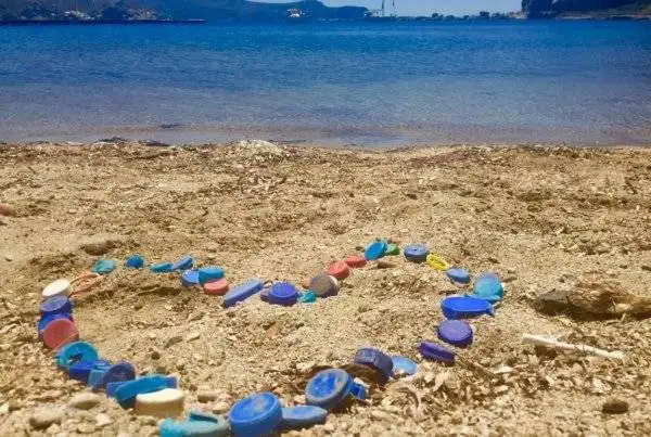a heart made of colorful glass beads on the beach.