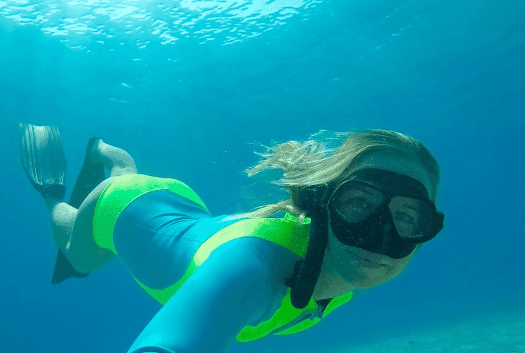 a woman in a blue swimsuit snorkling in the water.