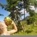 a woman drinking a coconut in the jungle.