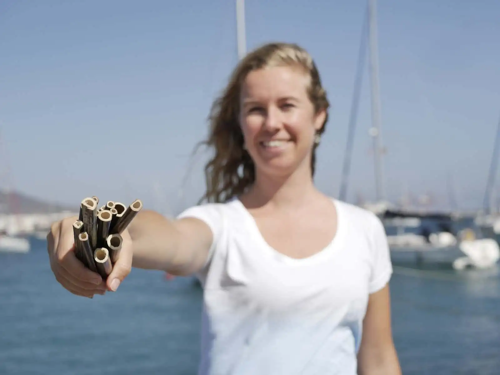 a woman holding a bunch of sticks in front of a boat.
