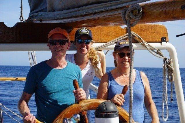 Three nomads on a sailboat's steering wheel navigating the vast ocean.