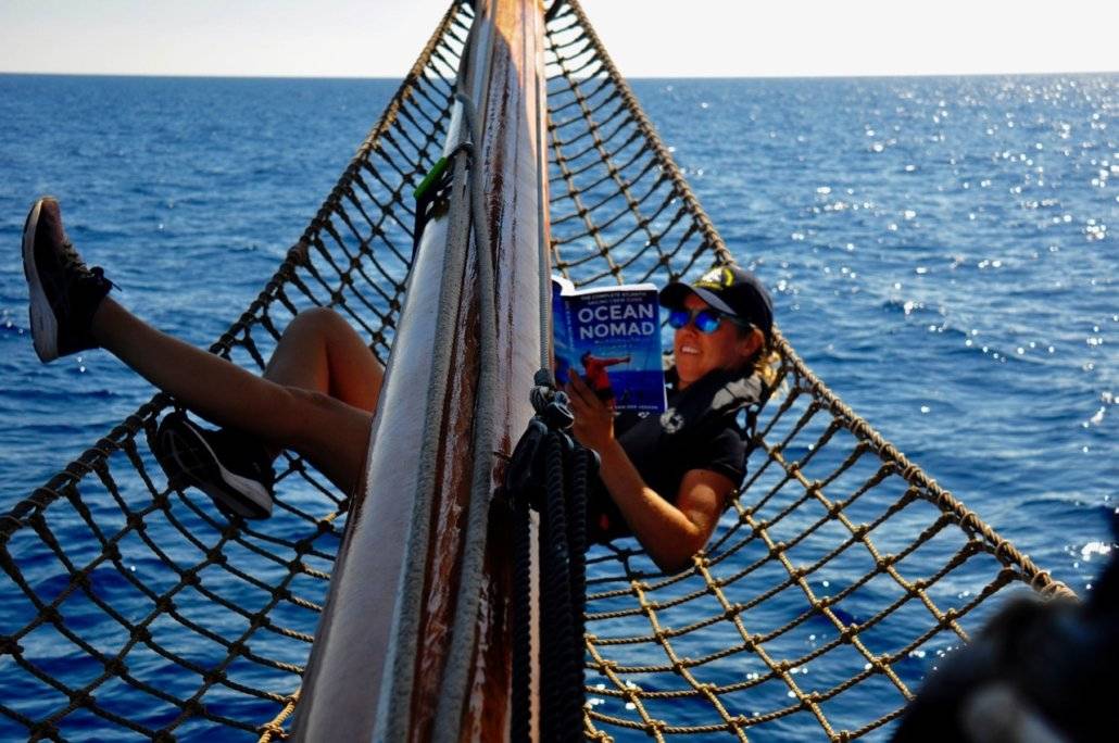 a woman reading a book on a sailboat.