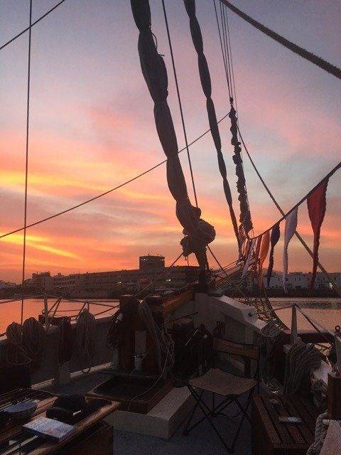 The oceanic deck of a tall ship basks in the enchanting hues of sunset.