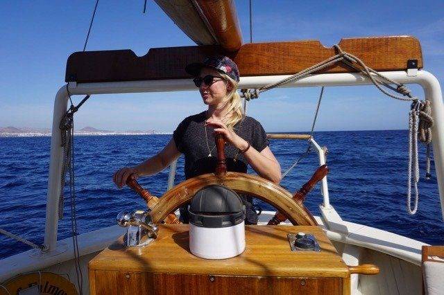 A woman steering the sailboat in the vast ocean.