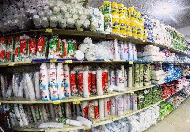 a store has a lot of toilet paper and plastic cups on the shelves.