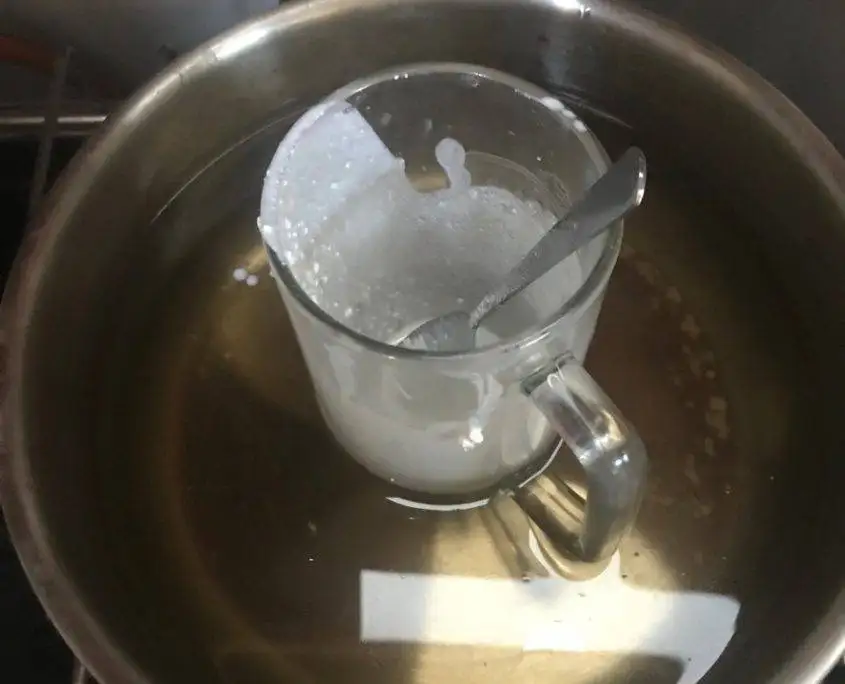 Melting DIY mineral sunscreen ingredients au bain marie in a glass bowl with shea and cacao butter