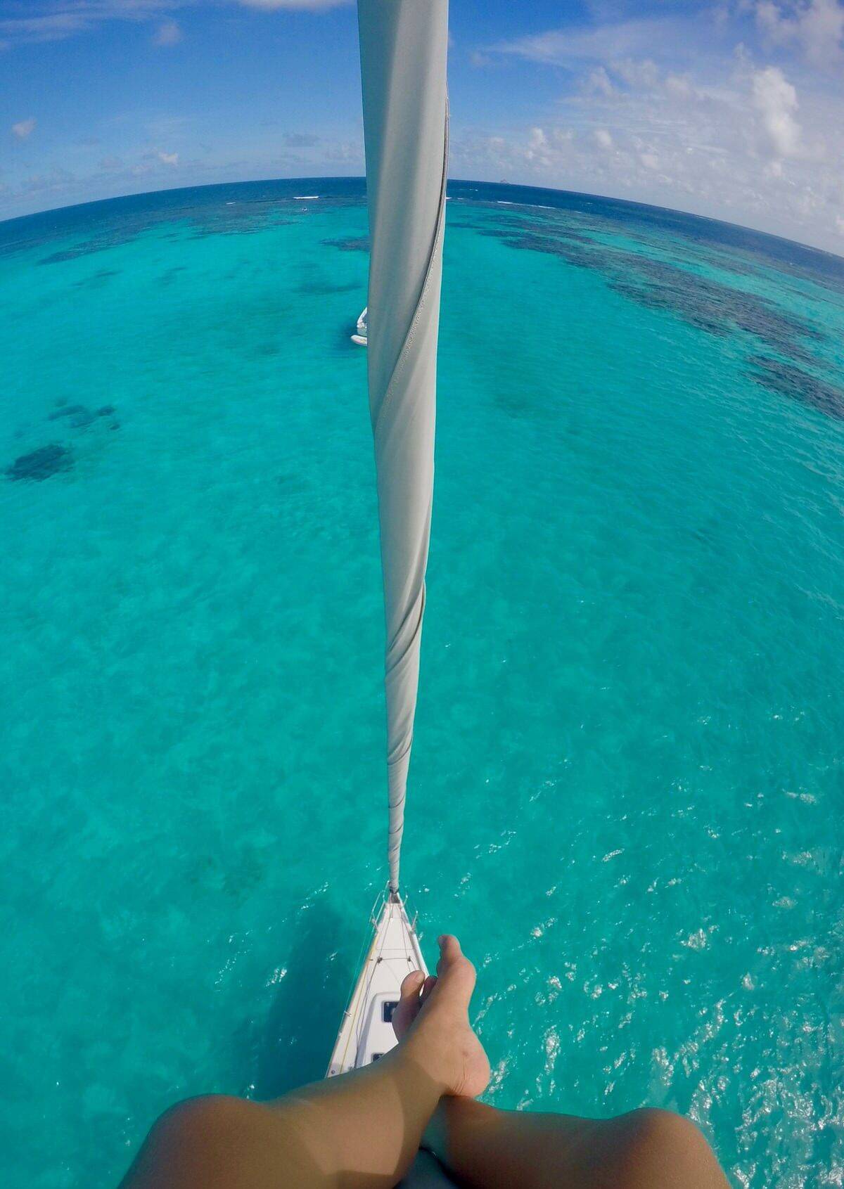 a person's feet on a sailboat in the ocean.
