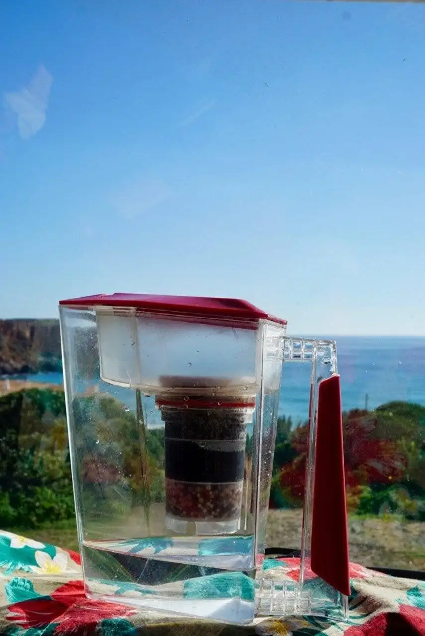 A travel water filter placed on a table overlooking the ocean.