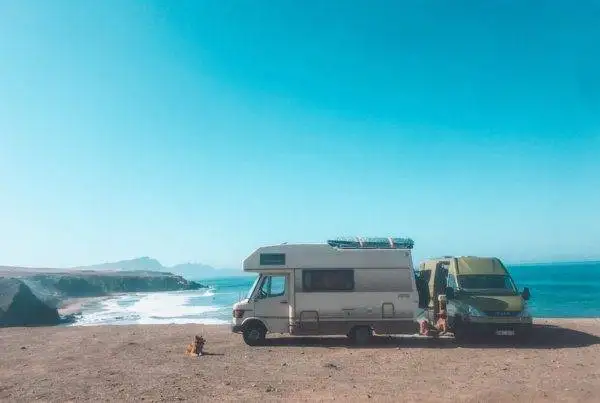 two rvs parked on the beach near the ocean.