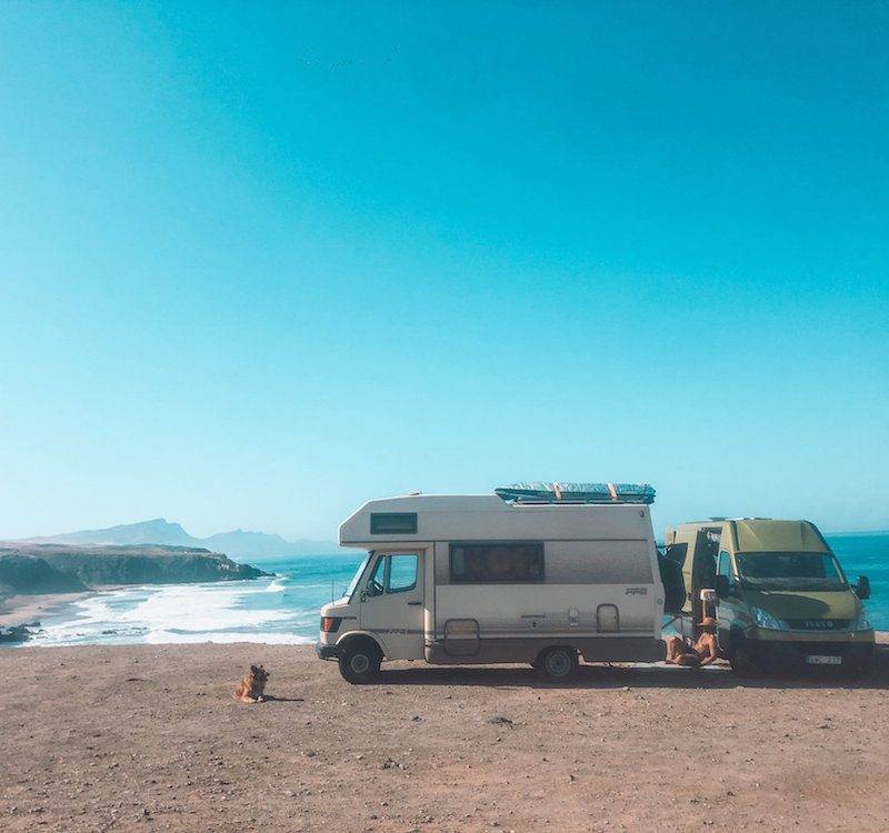 two rvs parked on the beach near the ocean.