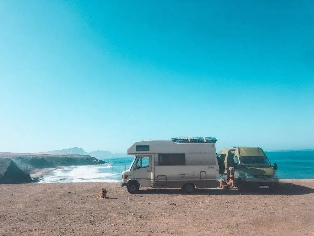 two rvs parked on the beach near the ocean.