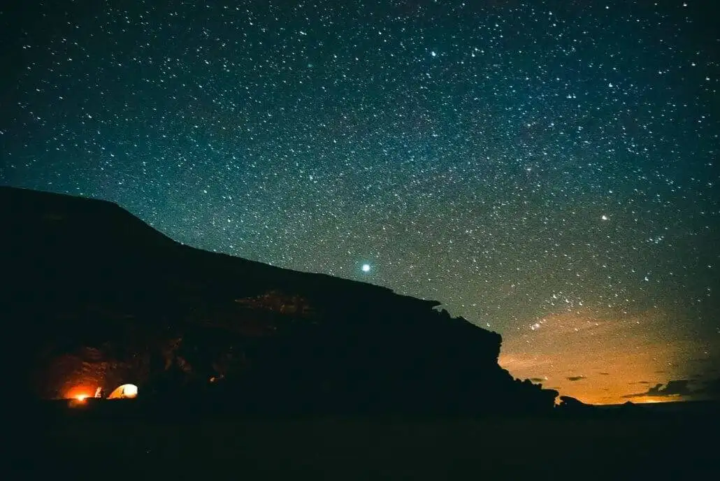 a starry night with a campfire on a beach.