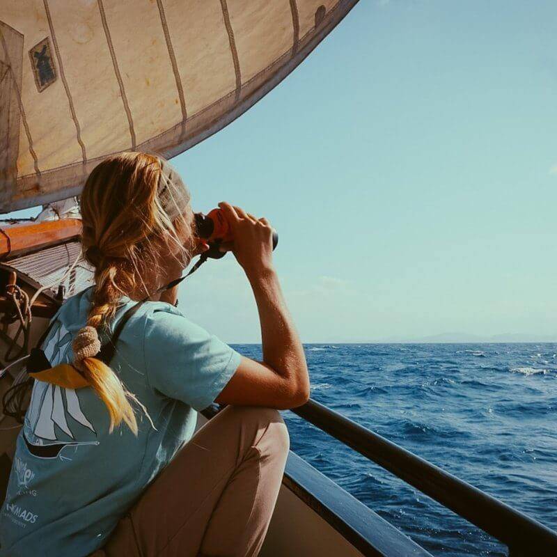 A woman sailing the Atlantic Ocean gazes out the window of a sailboat.