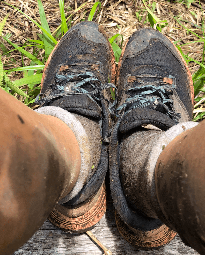 A person's feet in muddy Hiking/Sailing/Everything Shoes.