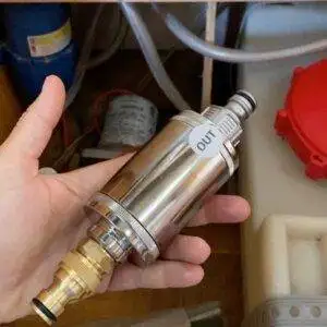 A person holding a Maunawai Campervan Waterfilter under a sink.