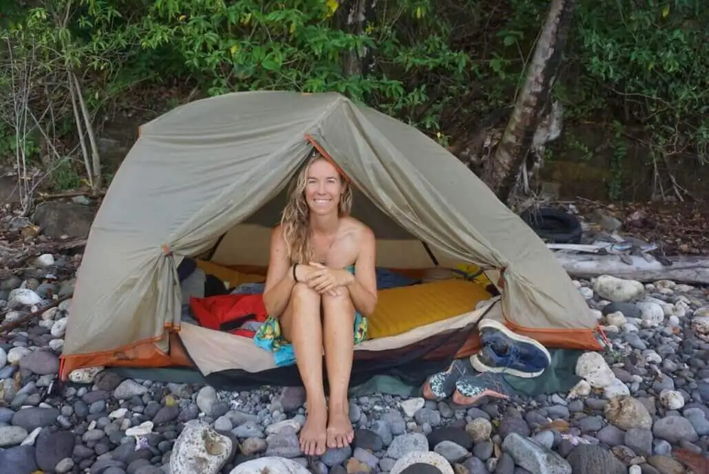 A woman sitting in front of a tent on the beach.