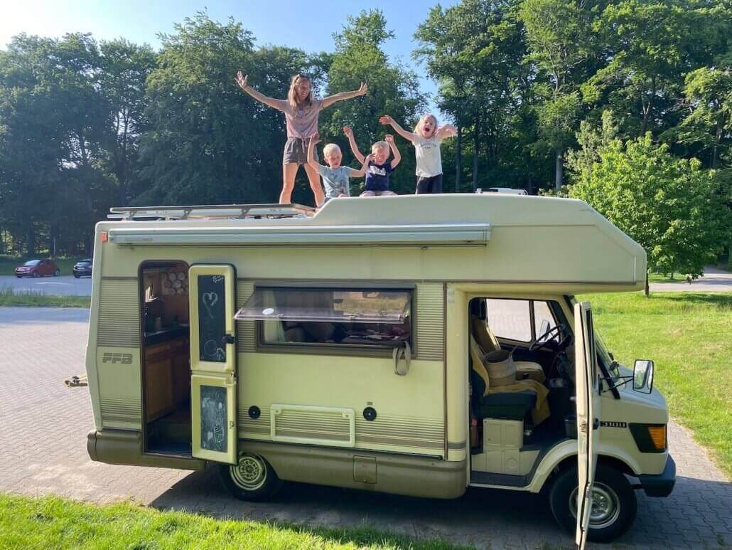 A group of people standing on top of a camper van.