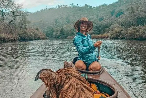 A woman in a canoe with her dog on the river.