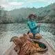 A woman in a canoe with her dog on the river.