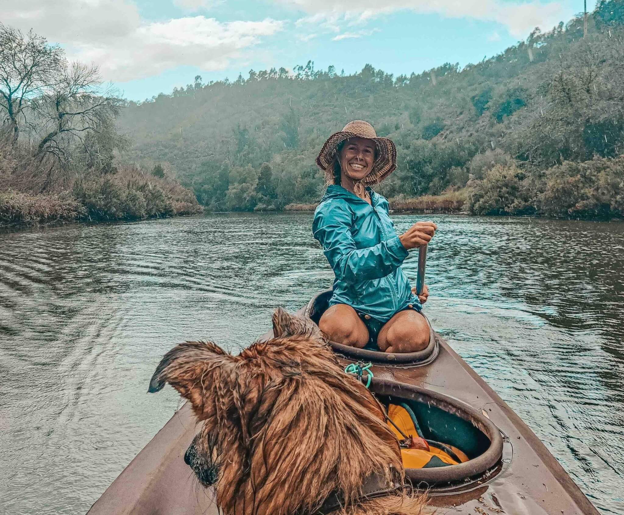 A woman in a canoe with her dog on the river.