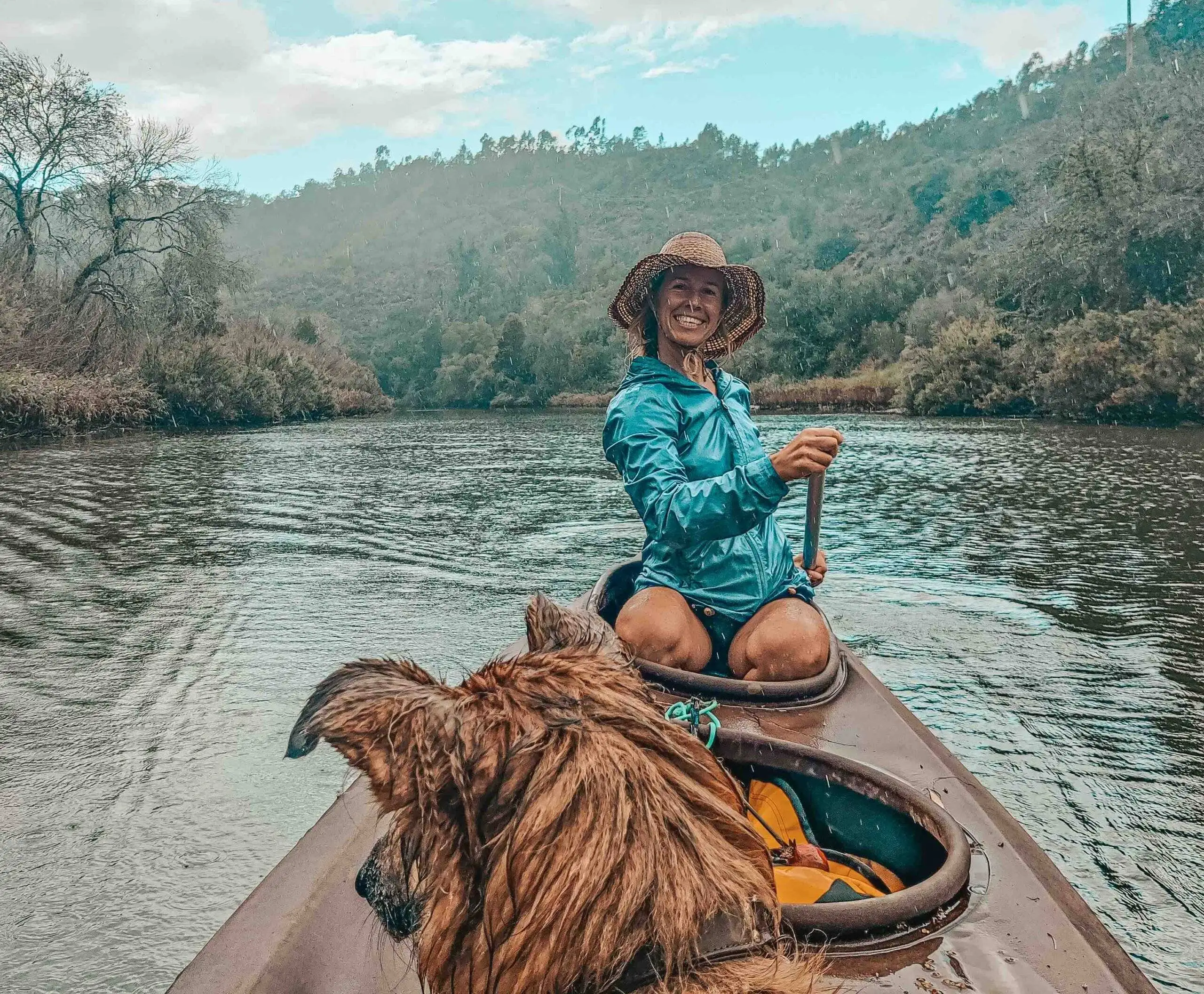 A woman in a canoe with her dog on the river.