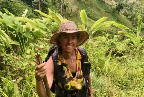 A woman wearing a hat and a backpack on a trail.
