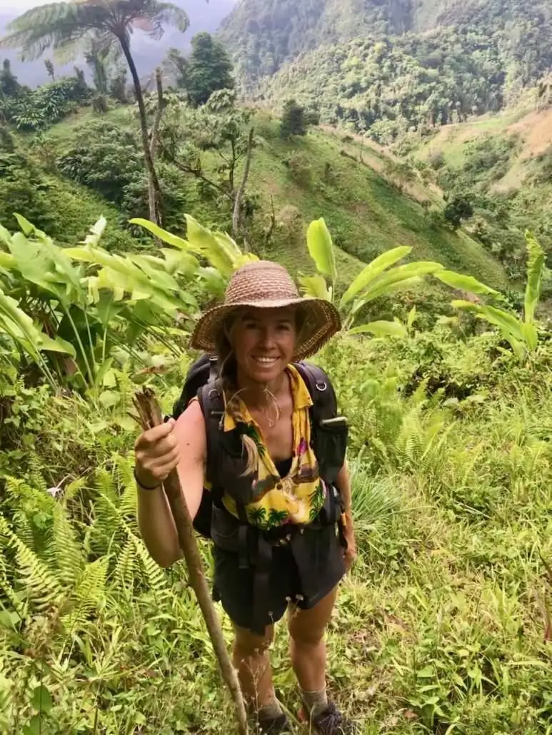 Suzanne wearing a hat and backpack on the Waitukubuli Trail end point.
