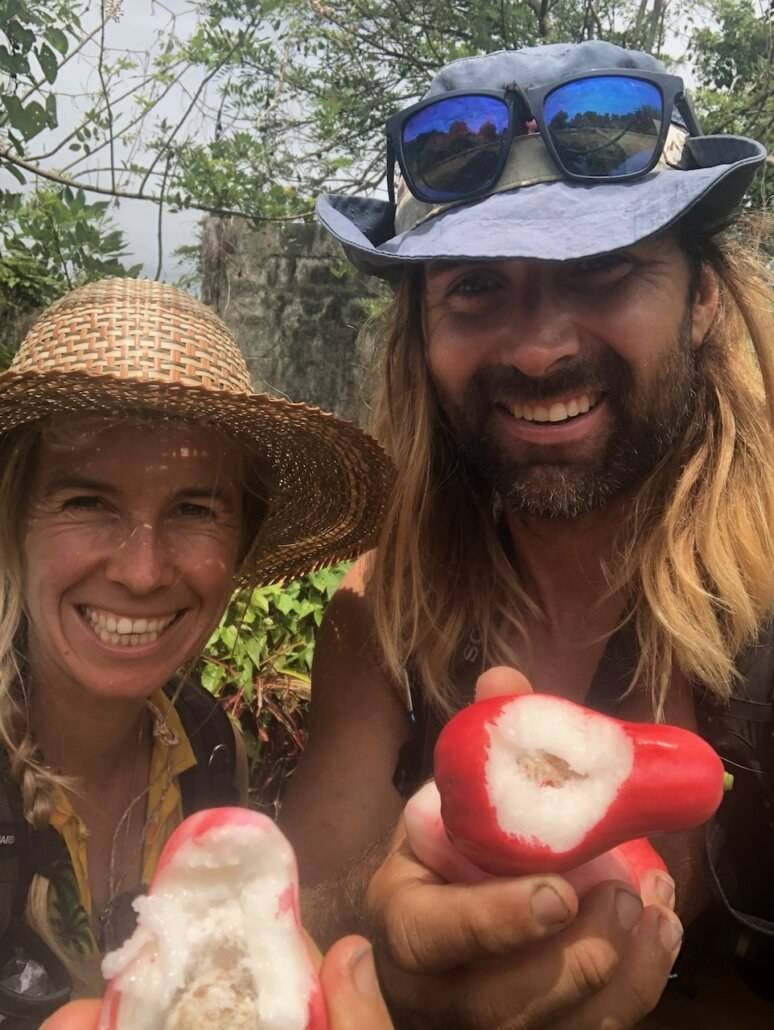 A man and a woman holding a fruit in their hands.