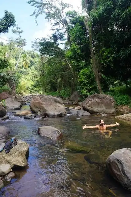 Suzanne floating in a river on the Waitukubuli Trail in Dominica.