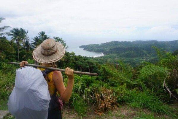 A woman with a backpack on a hill overlooking the ocean.