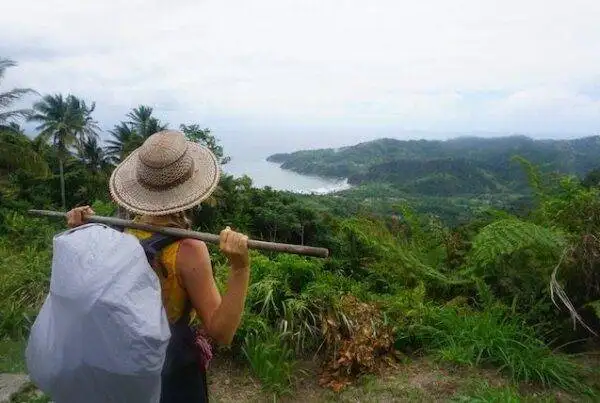 A woman with a backpack on a hill overlooking the ocean.