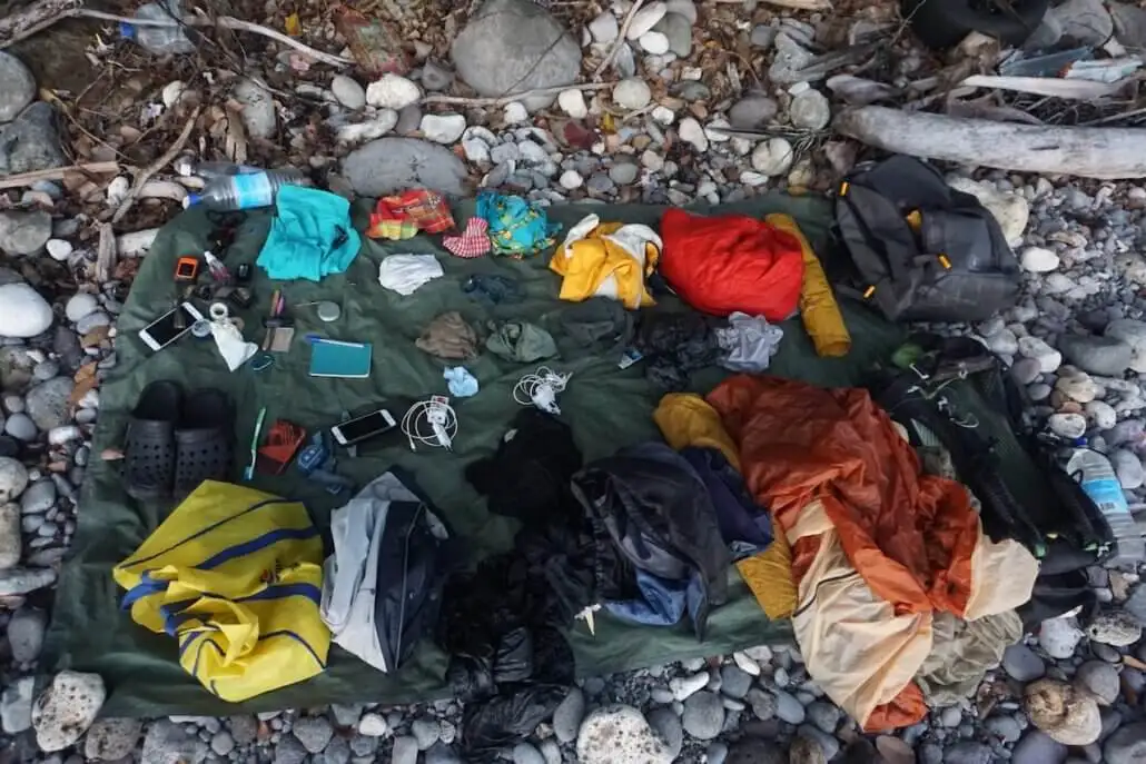A blanket laying on the ground with various items on it.