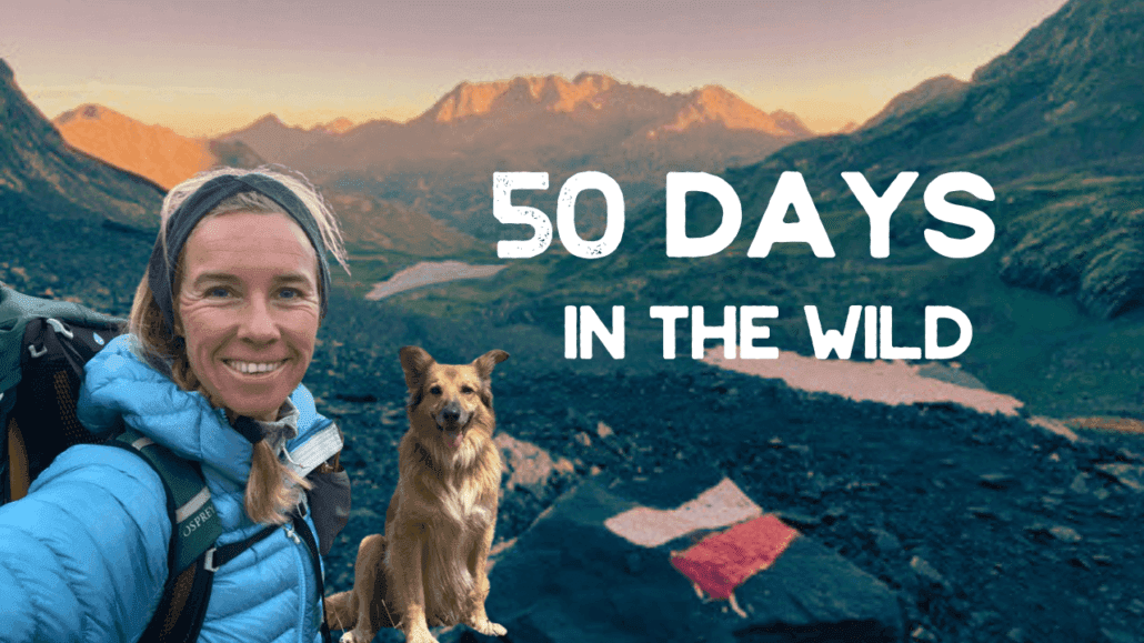 A woman in hiking gear and a dog pose on a rocky mountain trail at sunrise with "50 Days in the Wild" text overlaid on the image.