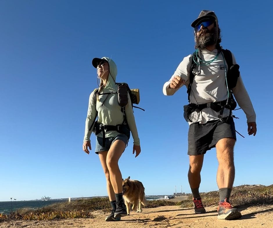 Hikers and a dog set off on the Fisherman's Trail at Praia de São Torpes, Portugal.
